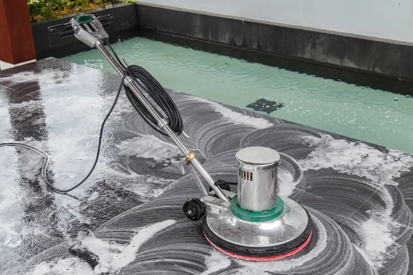 Thai people cleaning black granite floor with machine and chemic