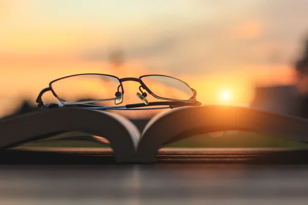 Close up glasses and book on table in sunset time