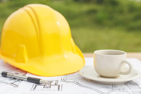 Close up coffee cup and Yellow safety helmet with floor plan dra