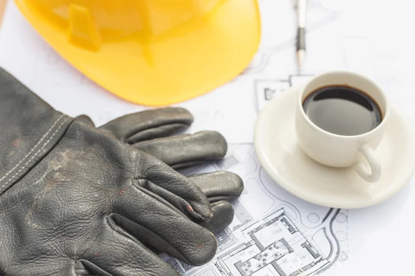 Close up work black glove with coffee, safety helmet and floor p