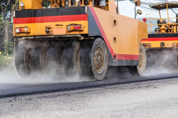 Road roller and asphalt paving machine at construction site