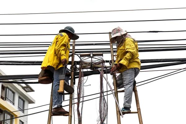 Worker on bamboo ladder is repairing telephone line