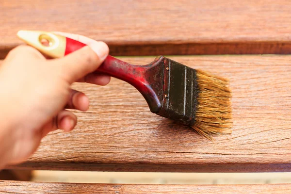 Hand holding brush and paint timber