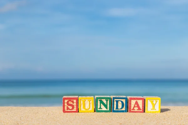 Word SUNDAY in colorful alphabet blocks on tropical beach