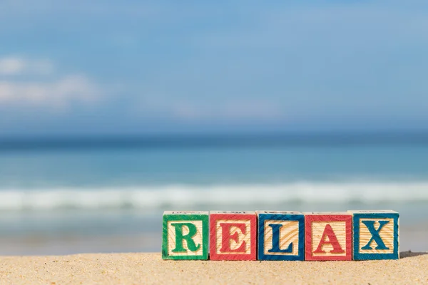 Word RELAX in colorful alphabet blocks on tropical beach