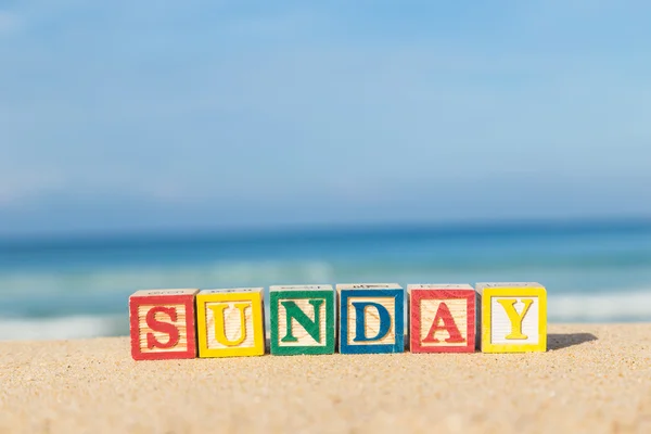 Word SUNDAY in colorful alphabet blocks on tropical beach