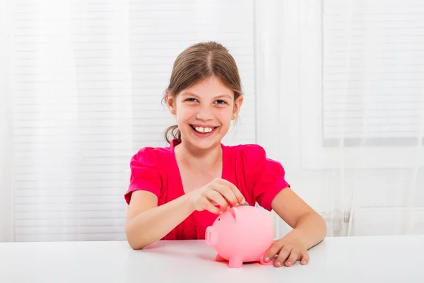 Girl putting coin into piggy bank
