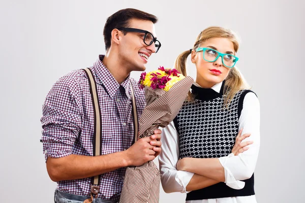 Nerdy man is giving a bouquet of flowers to his girlfriend