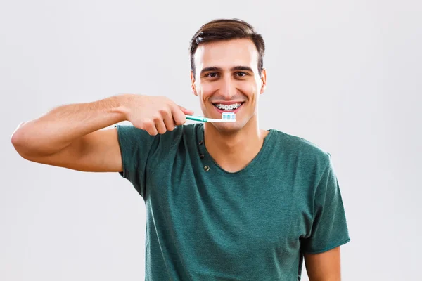Man with braces holding toothbrush.