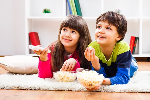 Little girl and little boy enjoy eating popcorn