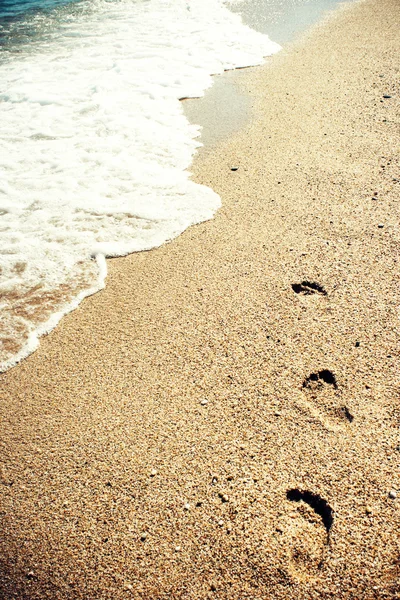 Footprints on sand at sunset