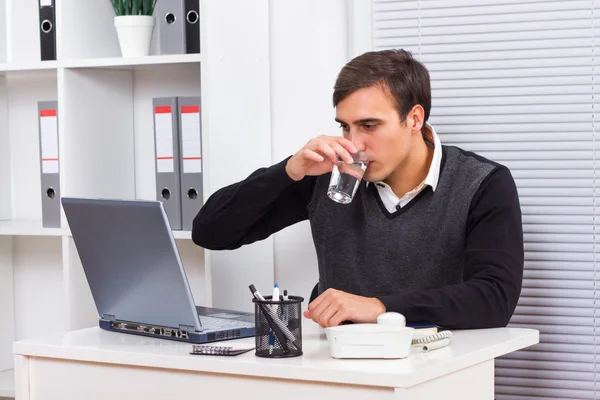 Business sitting in his office,working and drinking water