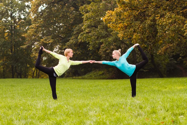 Friends practicing yoga in park