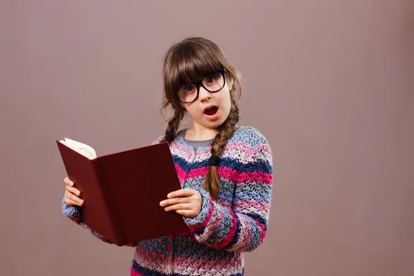Surprised little girl reading book