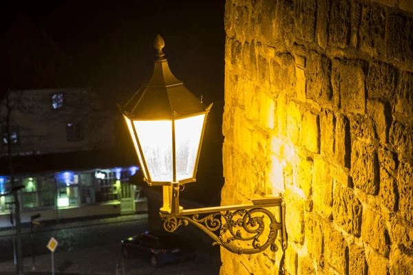 Traditional ancient street lamp on stone wall at night