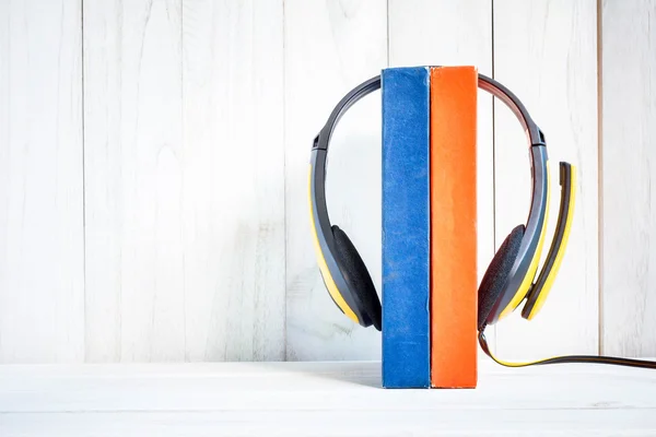Headphones on books on white wood background