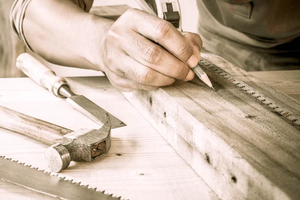 Close Up view of a carpenter using a straightedge to draw a line on a board.