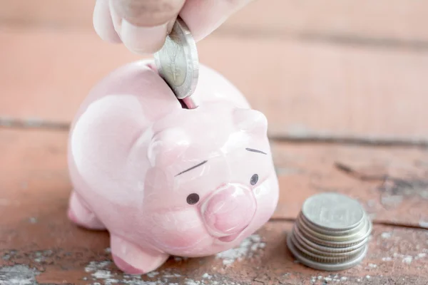 Male hand putting money In Piggy Bank, Saving money concept.