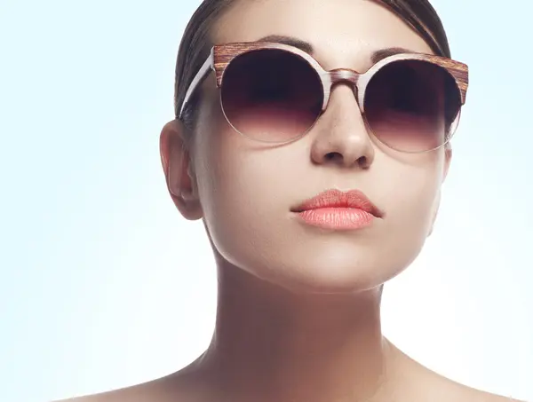Young female fashion model wearing big sunglasses on white backg