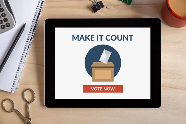 Online voting concept on tablet screen with office objects on wo