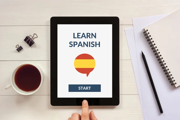 Online learn spanish concept on tablet screen with office objects