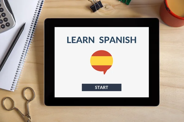 Online learn spanish concept on tablet screen with office objects