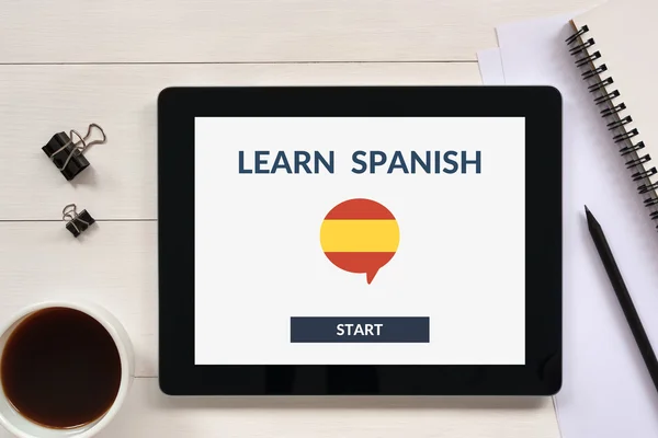 Online learn spanish concept on tablet screen with office objects