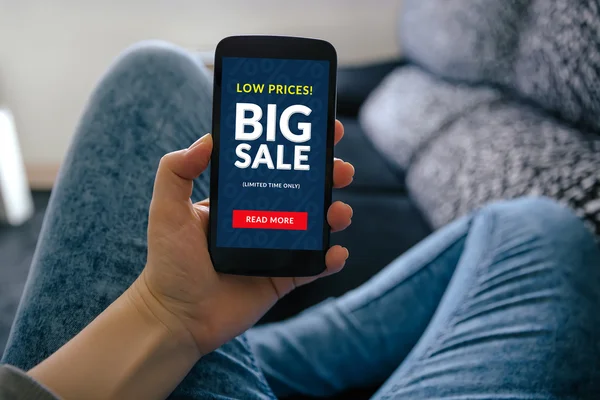 Girl holding smart phone with big sale concept on screen