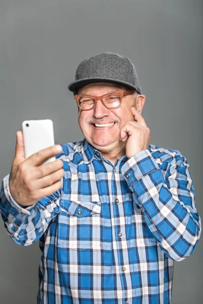 Old active man using mobile phone isolated on grey background