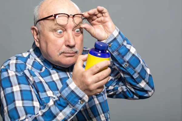 Happy old man holding bottle with vitamins