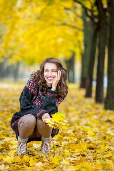 Fall Fashion. Autumn woman in park in knitted autumn clothes over yellow  leaves around. Girl relax enjoy nature