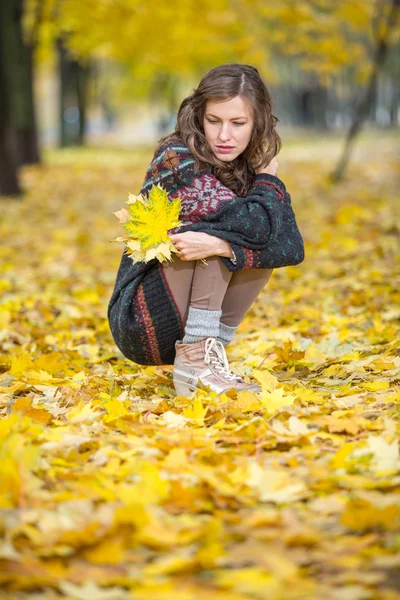 Fall Fashion. Autumn woman in park in knitted autumn clothes over yellow  leaves around. Girl relax enjoy nature. Autumn sadness concept