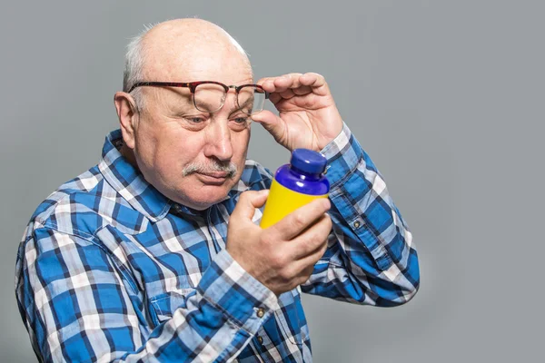 Happy old man holding bottle with vitamins