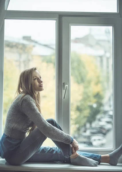 Beautiful young woman sitting by the window