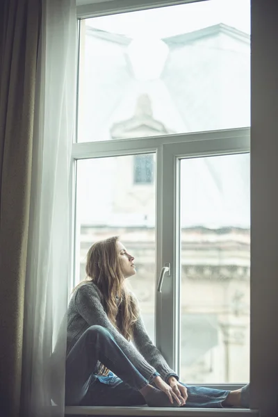 Beautiful young woman sitting by the window