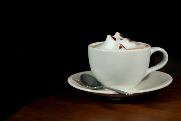 A cup of coffee cappuccino with milk foam in a white cup on blac