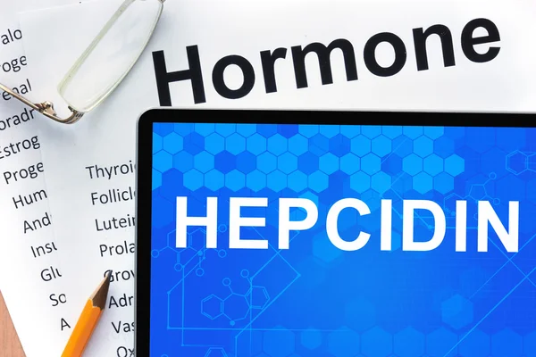 Papers with hormones list and tablet with words hepcidin .