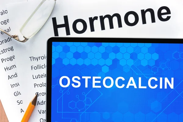 Papers with hormones list and tablet with words osteocalcin.