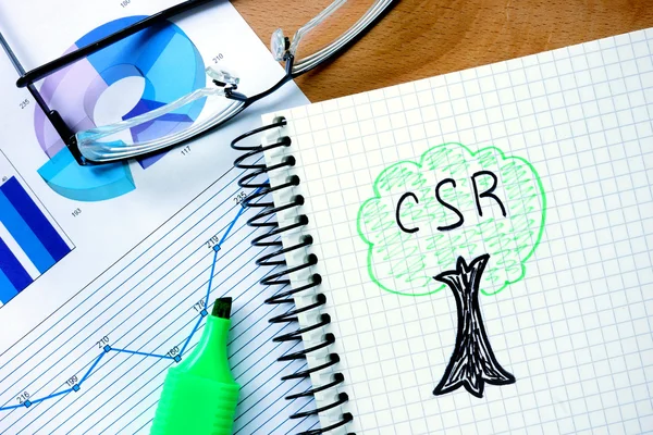 Notepad with  csr  Corporate social responsibility  on office wooden table.
