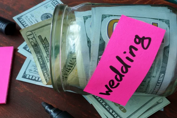Jar with label wedding and money on the table.