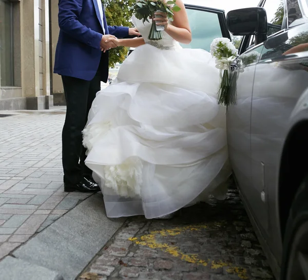 Beautiful couple, bride and groom getting into wedding limousine
