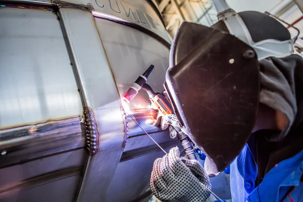 Man welding with reflection of sparks on visor. Hard job.