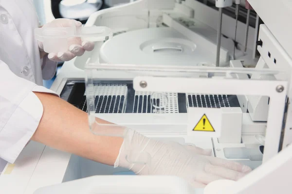 Lab tech loading samples into a chemistry analyzer