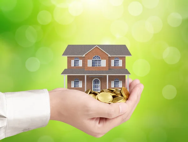 Businessman holding home model and coins