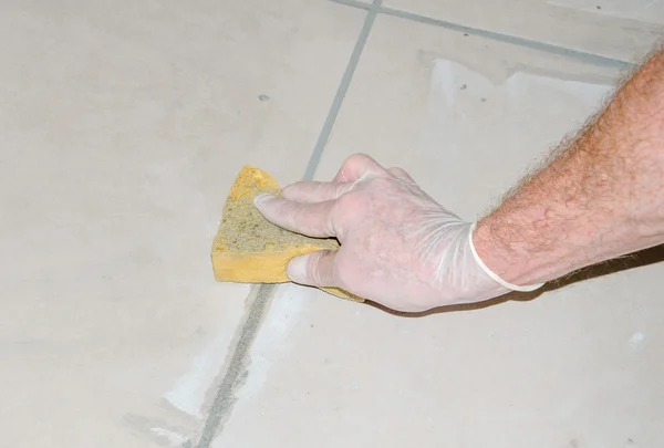 Tiler smoothing tile joints with a sponge