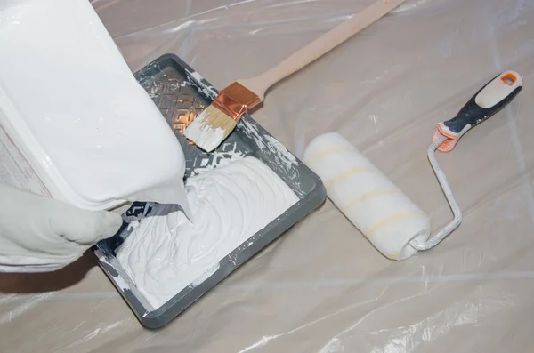 Painter pouring white paint