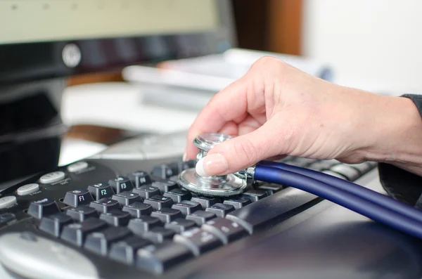 Woman's hand checking a keyboard with a stethoscope