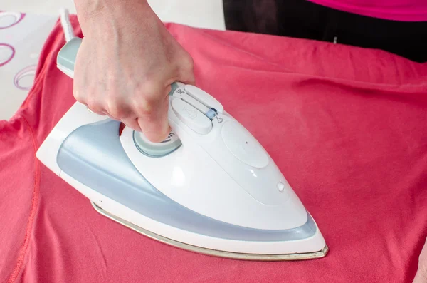 Woman ironing a tee shirt