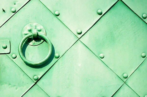 Vintage metal background - Old green door with rivets and aged metal door handle in the form of ring