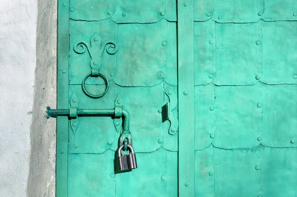 Old metal light turquoise door with rivets, plates and aged metal door handle
